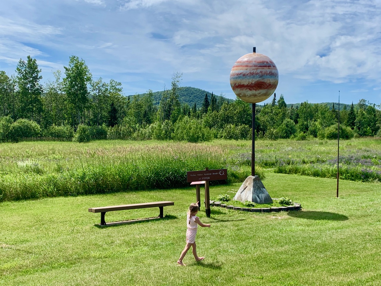 a young girl approaches a planet at one of the stops along the Maine Solar System Model